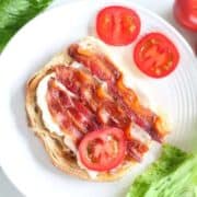 Slice of toasted sourdough bread spread with mayonnaise and topped with slices of tomato