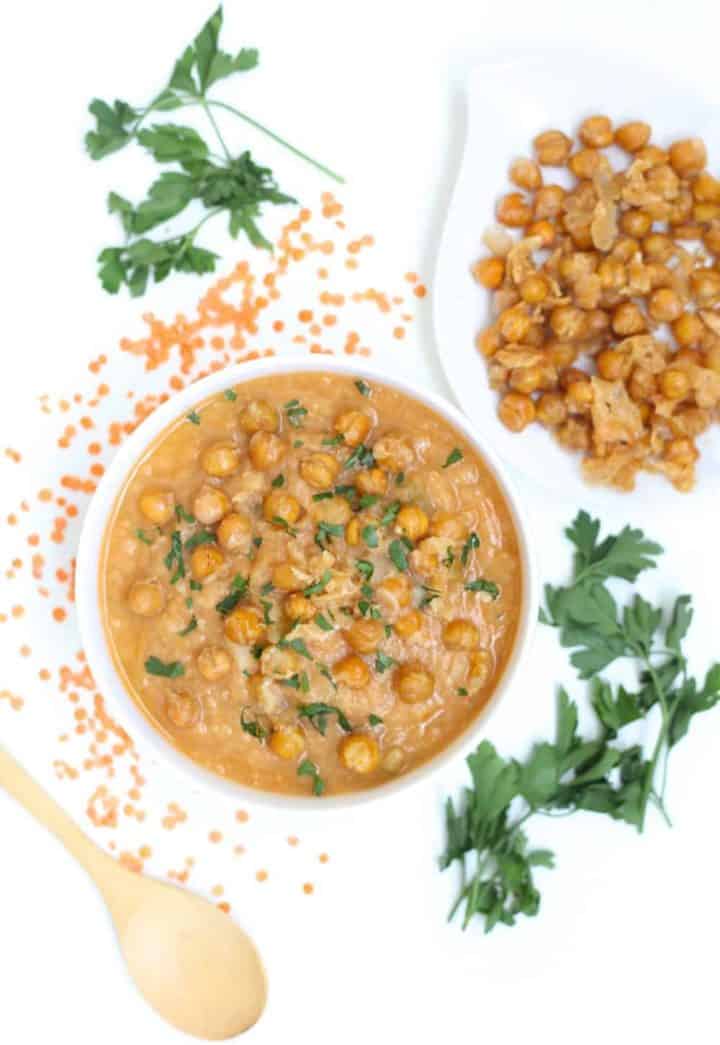 Red lentil soup in a white bowl topped with crispy parmesan chickpeas