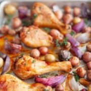 Sheet pan with cooked chicken drumsticks and baby potatoes in a citrus thyme marinade