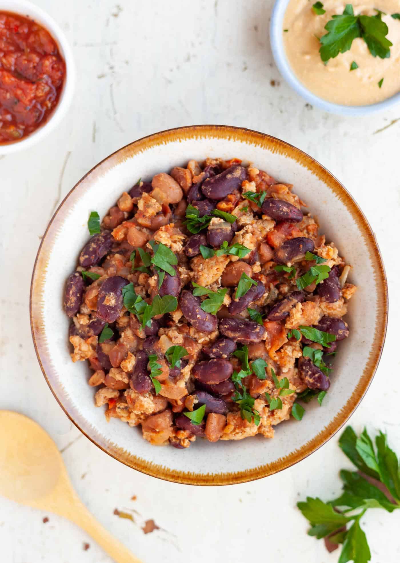 Bowl filled with turkey and bean chili garnished with parsley