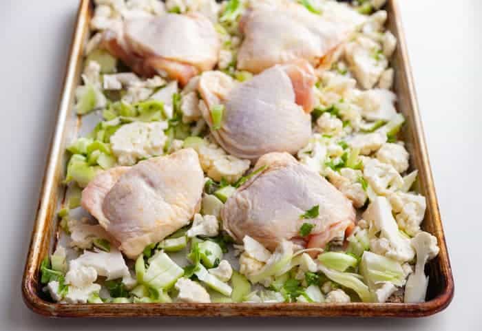 Sheet pan of raw chicken thighs and chopped cauliflower