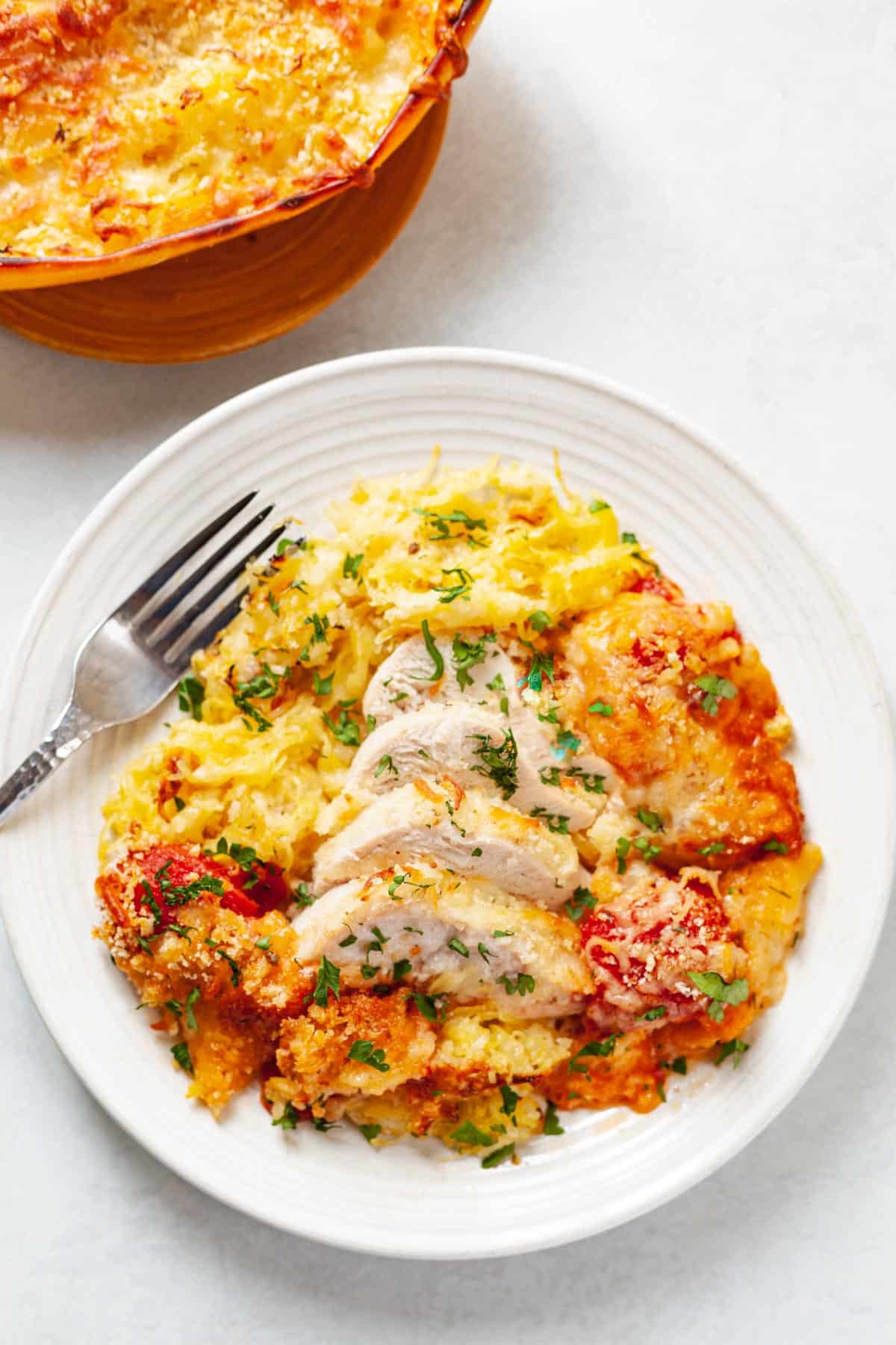 plate of sliced chicken breast and roasted spaghetti squash with tomato sauce, mozzarella, panko and parmesan