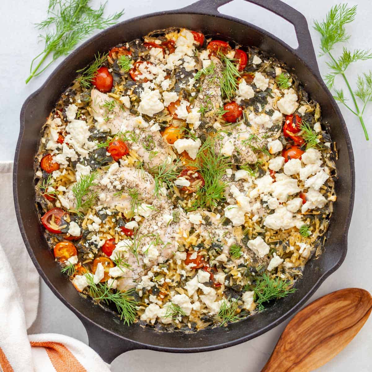 skillet with baked orzo, chicken, feta and tomatoes topped with dill