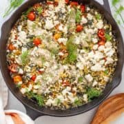 Cast iron skillet of baked orzo and chicken tenders with feta, tomatoes, spinach & dill