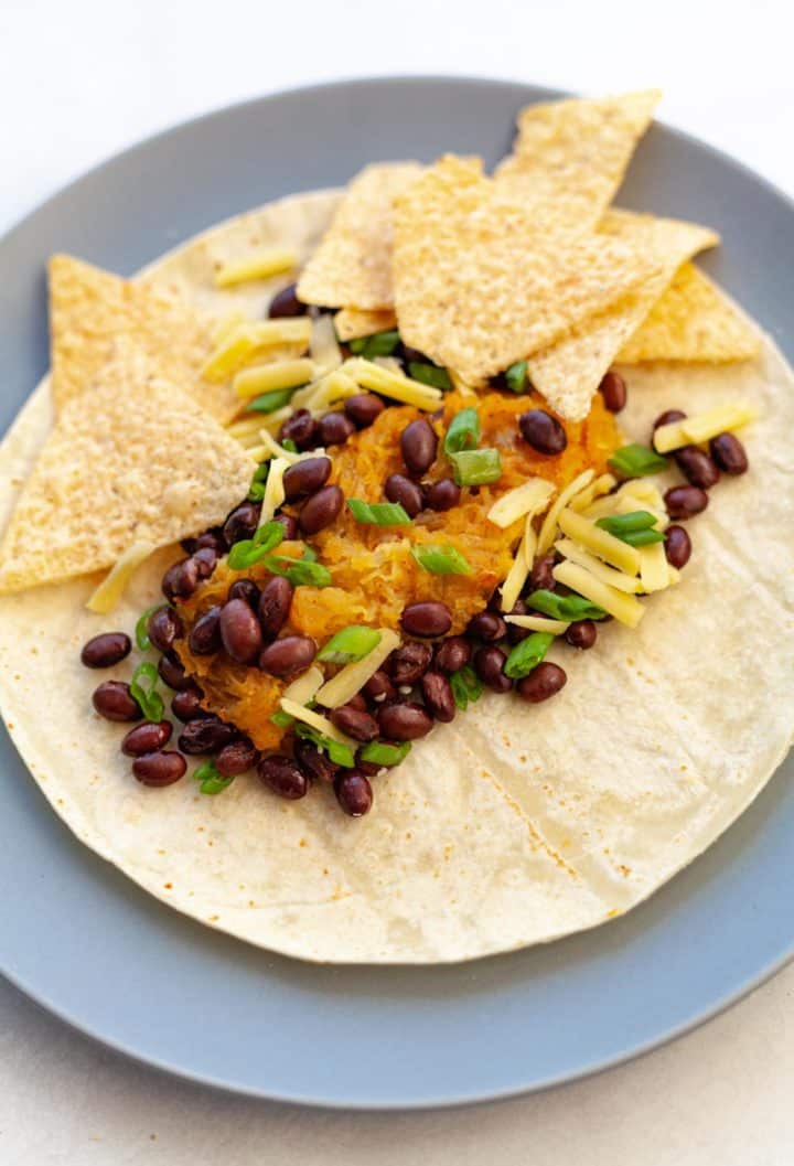 strands of spaghetti squash baked with cheese, green chiles and black beans in a flour tortilla with chips on the side