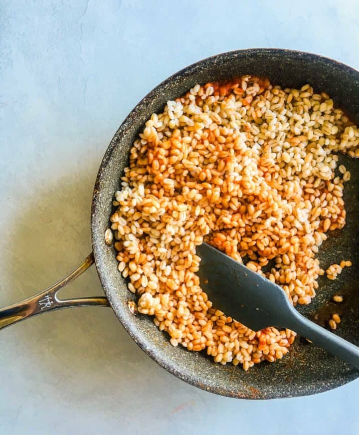 saute pan with cooked barley and tomato paste