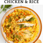 Bowl with with turmeric rice with flecks of carrot and dill and slices of chicken