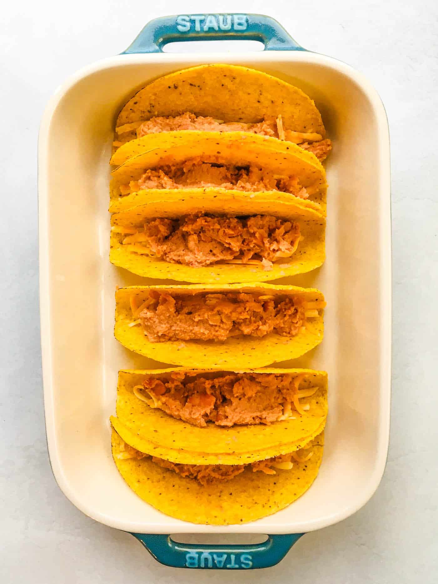hard taco shells filled with grated cheese and refried beans