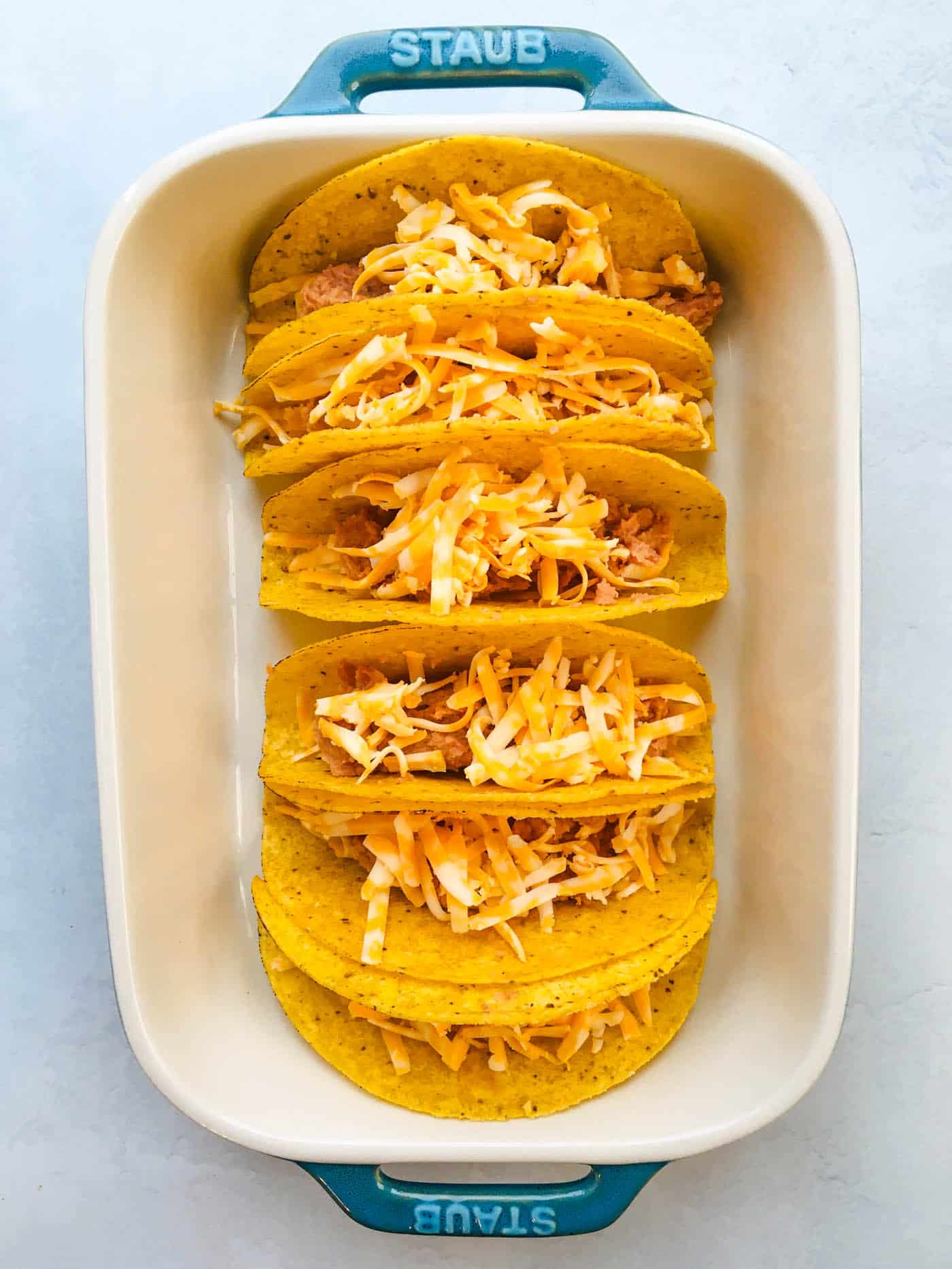 hard taco shells filled with grated cheese and refried beans