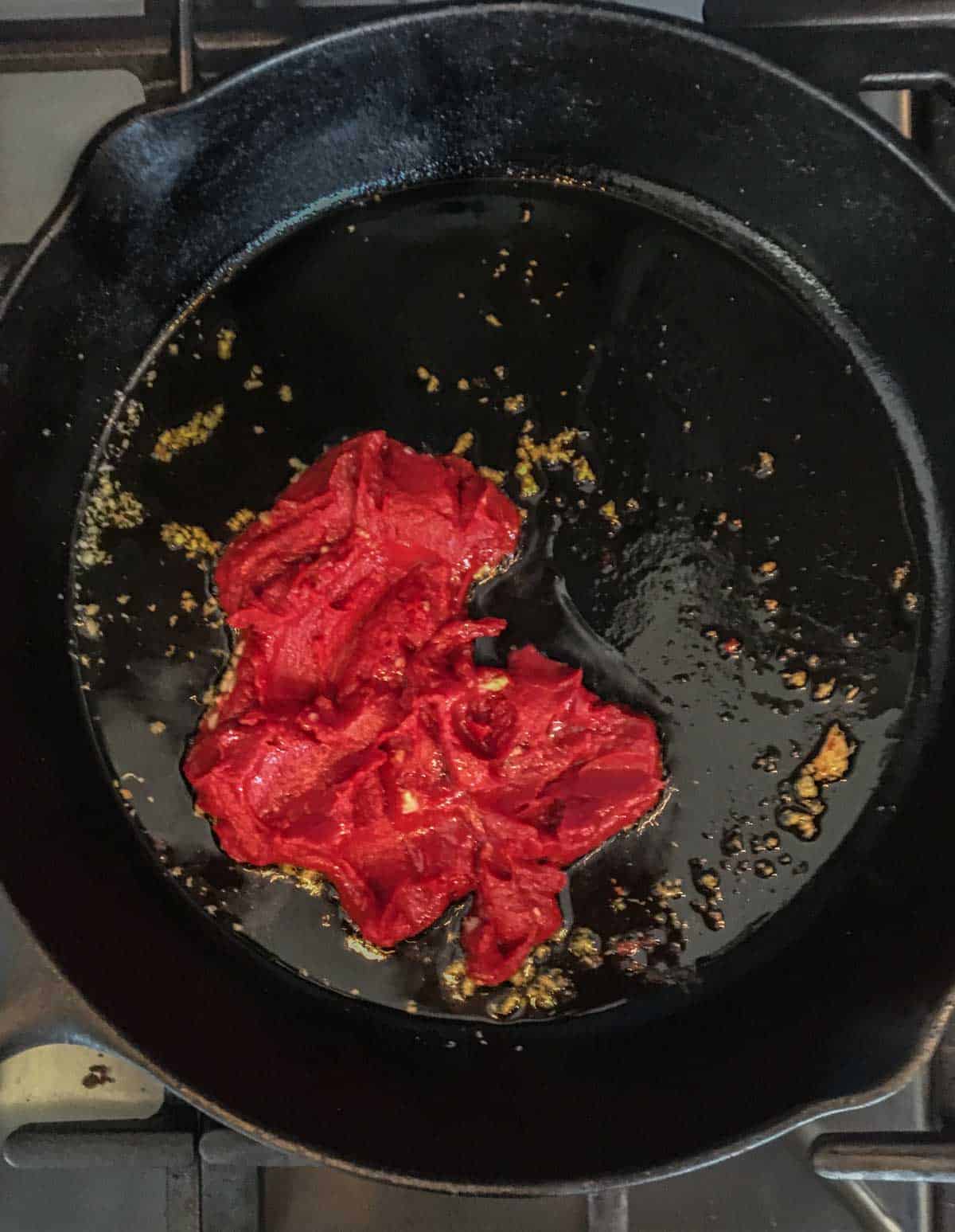 cast iron skillet with tomato paste and garlic