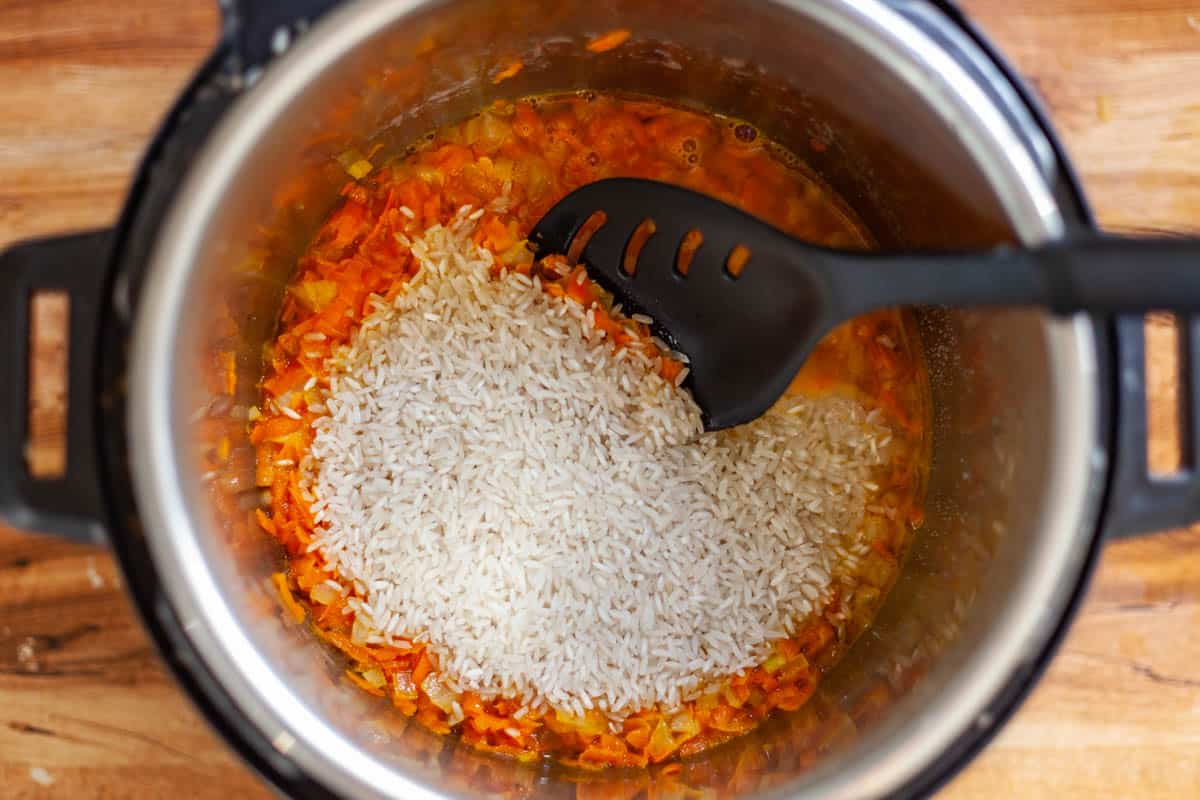 carrot, onion and uncooked white rice in a pressure cooker