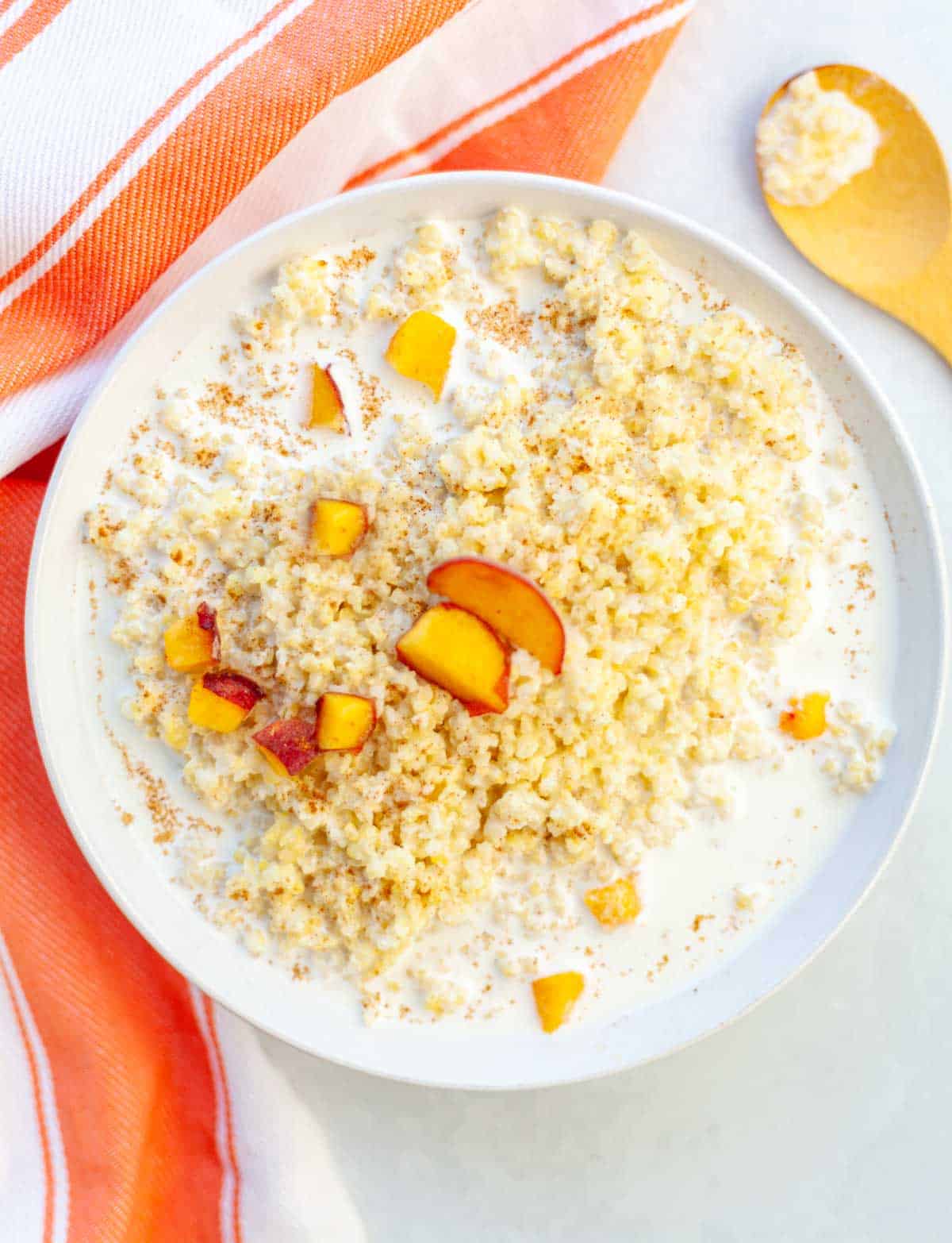 bowl of millet porridge with milk, peaches and cinnamon