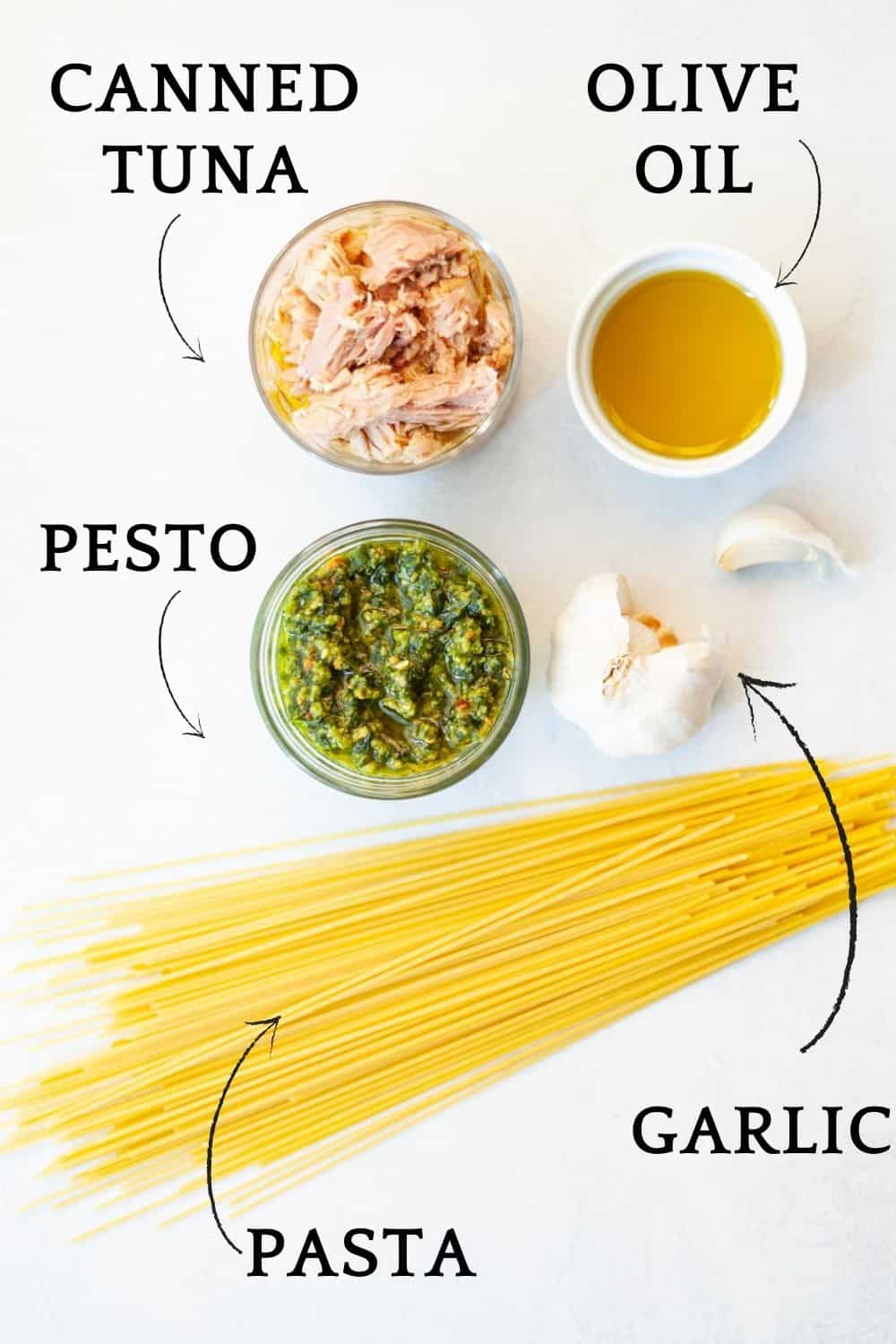 ingredients for pesto tuna pasta, such as dry pasta, garlic, olive oil, pesto and canned tuna