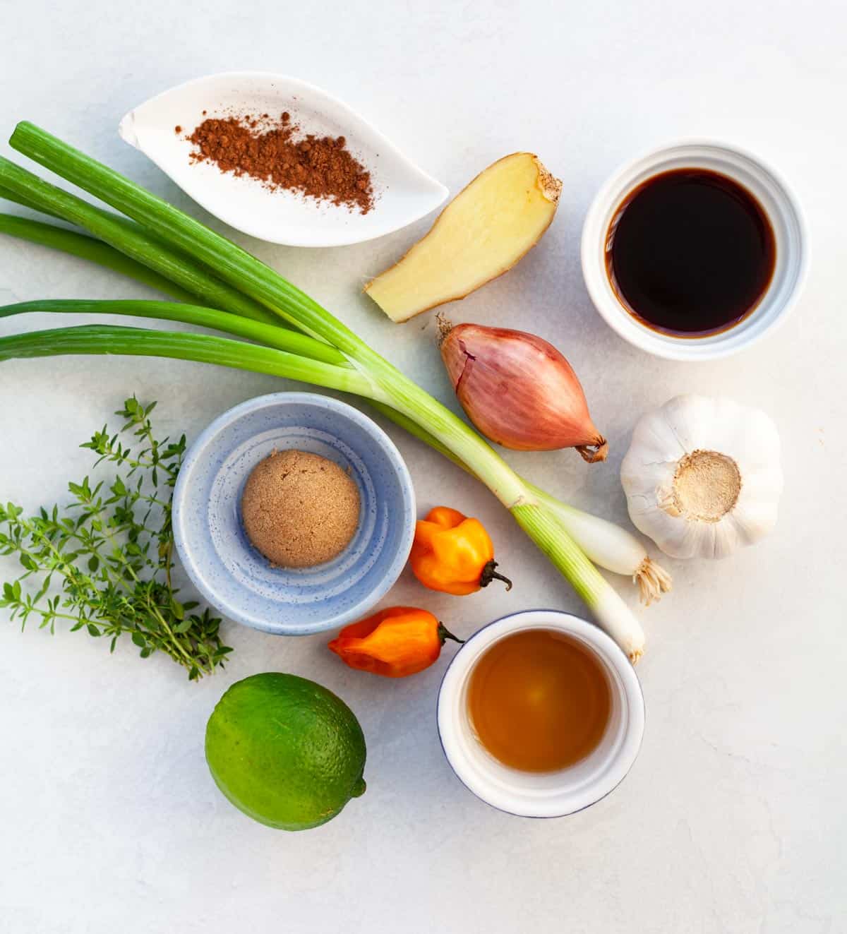 ingredients for jerk chicken, such as lime, ginger, garlic, hot pepper, green onion, shallot, brown sugar, soy sauce, thyme and vinegar