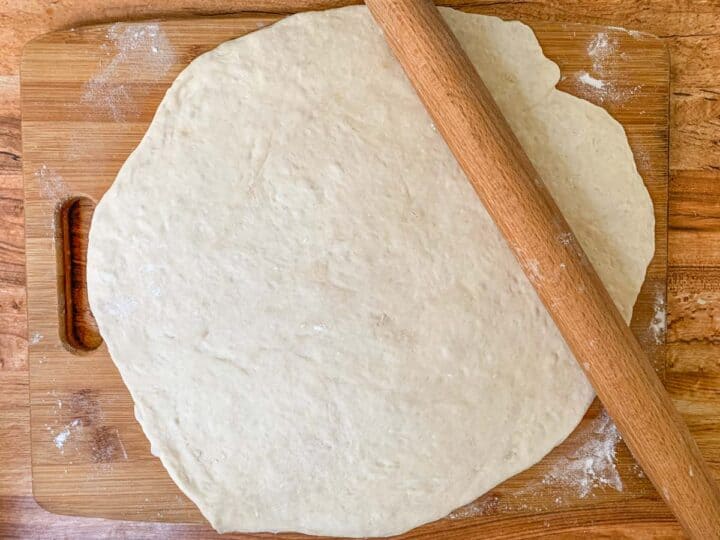 pizza dough rolled out on a cutting board