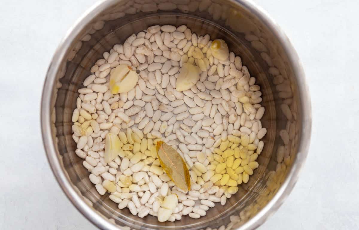 dried white beans, garlic cloves, bay leaf, olive oil and salt in a pressure cooker pot.