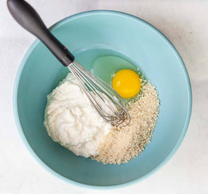 a bowl of ricotta, panko and an egg with a whisk