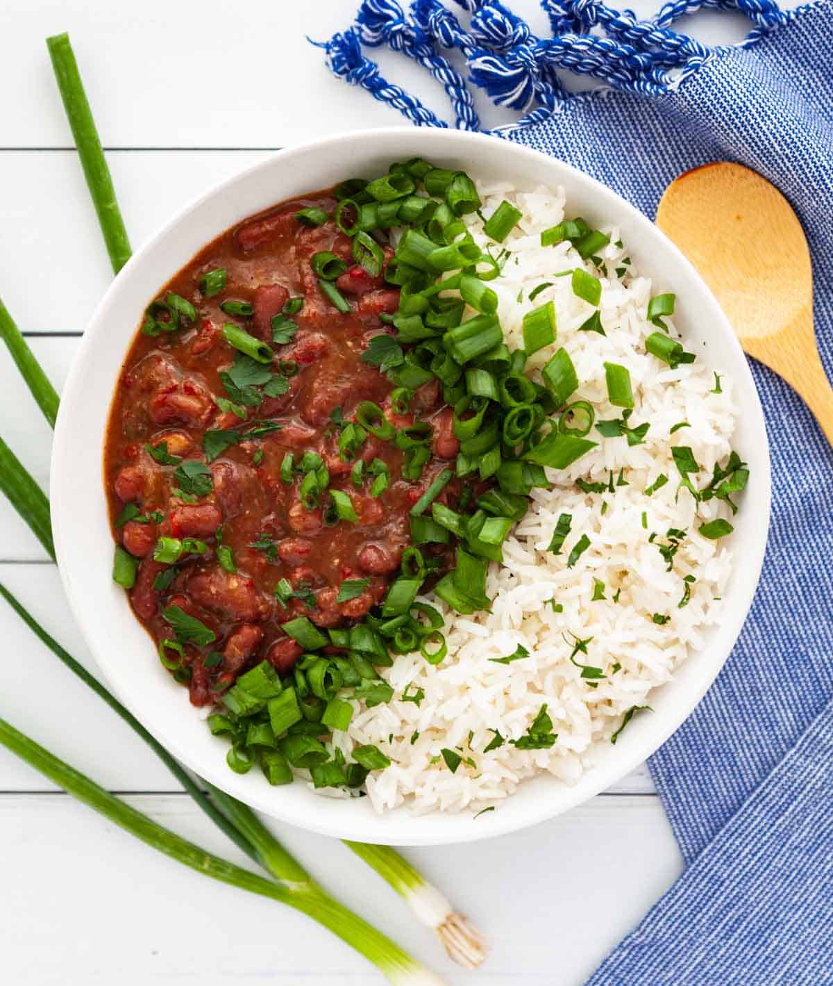 bowl of stewed red beans and white rice garnished with green onion