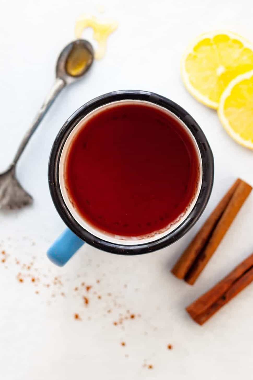 mug of cinnamon tea surrounded by cinnamon sticks, lemon and honey