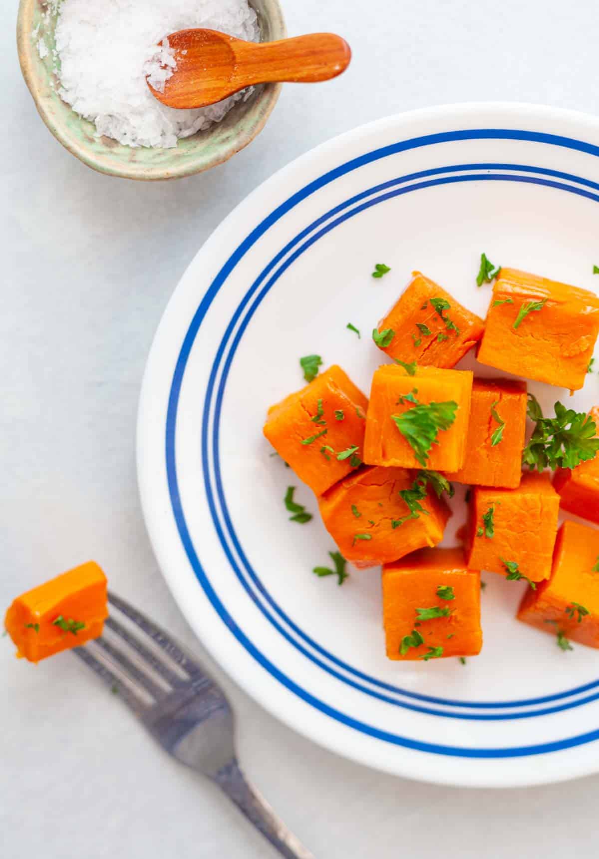 a plate and fork with cubes of steamed sweet potato chunks