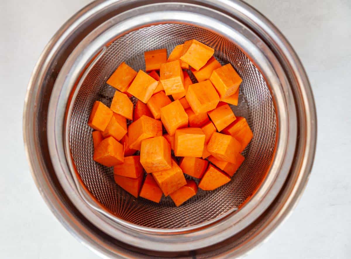 cubes of sweet potato in the steamer basket of a pressure cooker