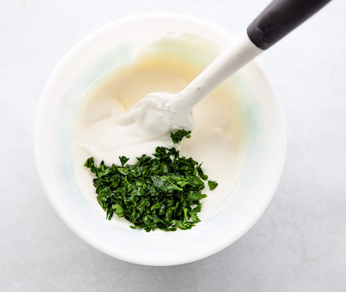 a bowl of creme fraiche dressing with chopped parsley