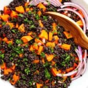 a serving bowl of black lentil salad with sweet potatoes