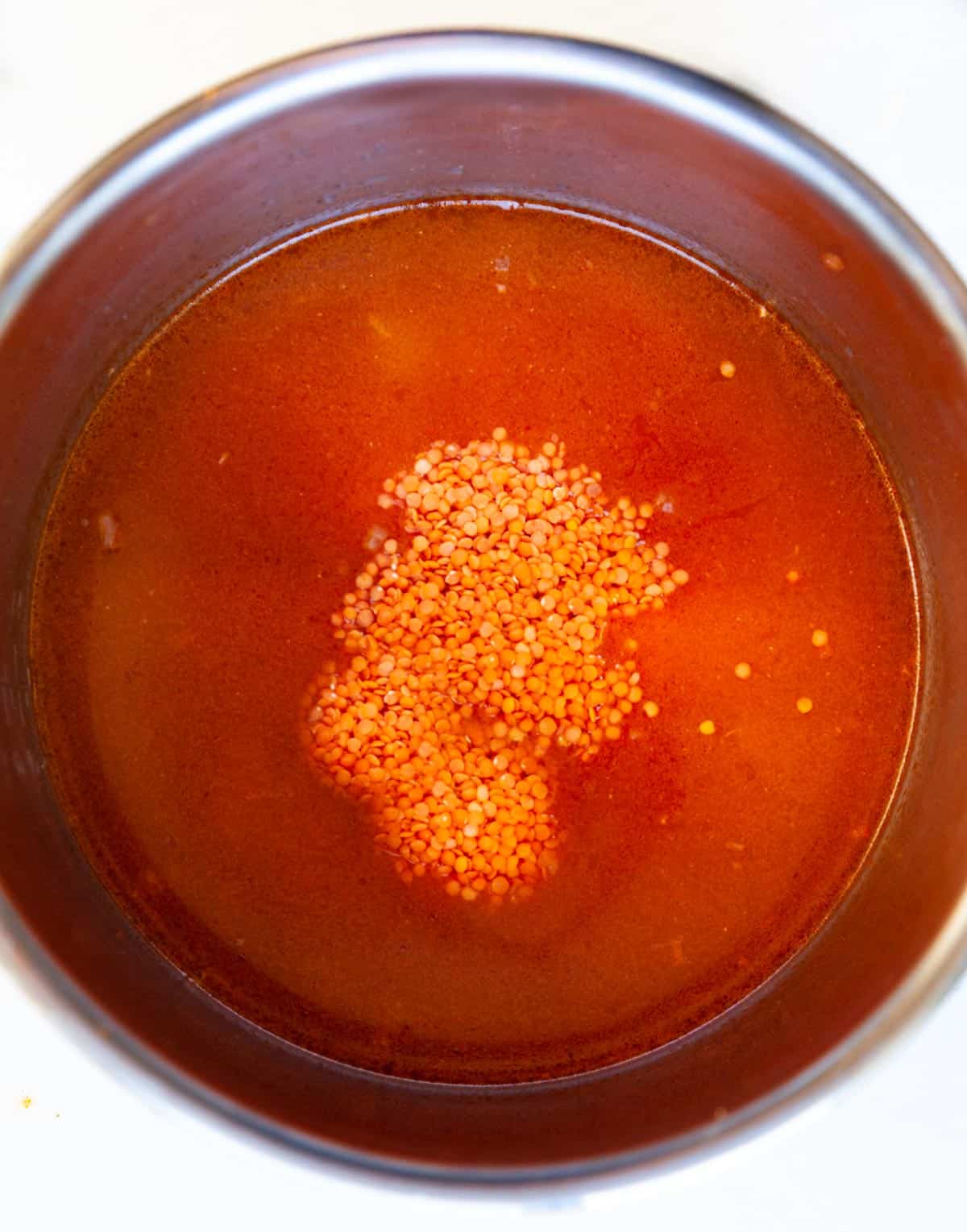 red lentils in a pot with tomato paste and broth
