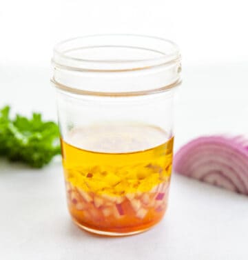 a jar of homemade maple dijon salad dressing with shallots