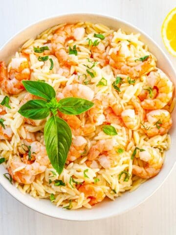 bowl of orzo and shrimp garnished with basil