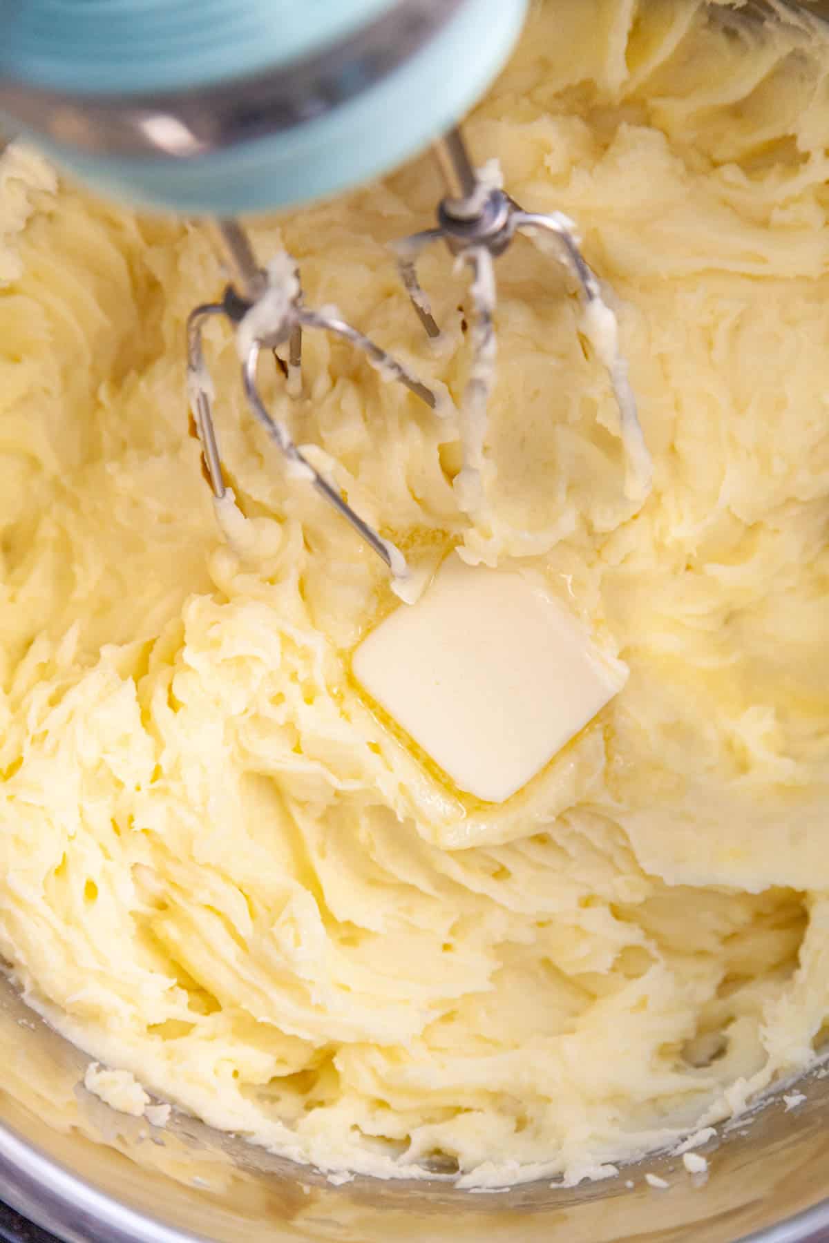 a hand-held mixer mixing a bowl of mashed potatoes