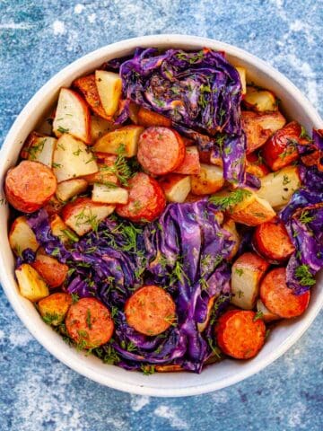 a bowl of sliced kielbasa with roasted potatoes and purple cabbage