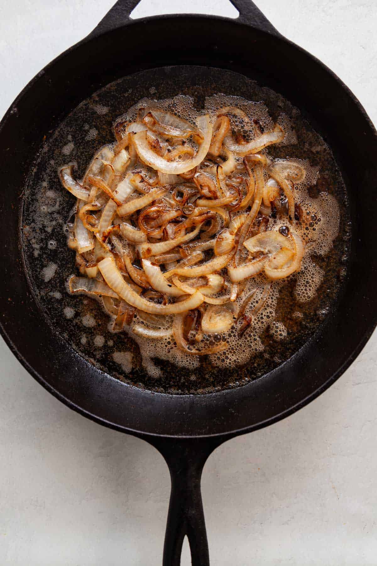 hard cider simmering in a skillet with cooked onion