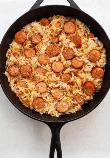 slices of kielbasa in a skillet of sauerkraut