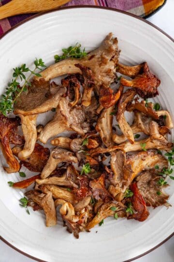 a plate of roasted oyster mushrooms garnished with thyme