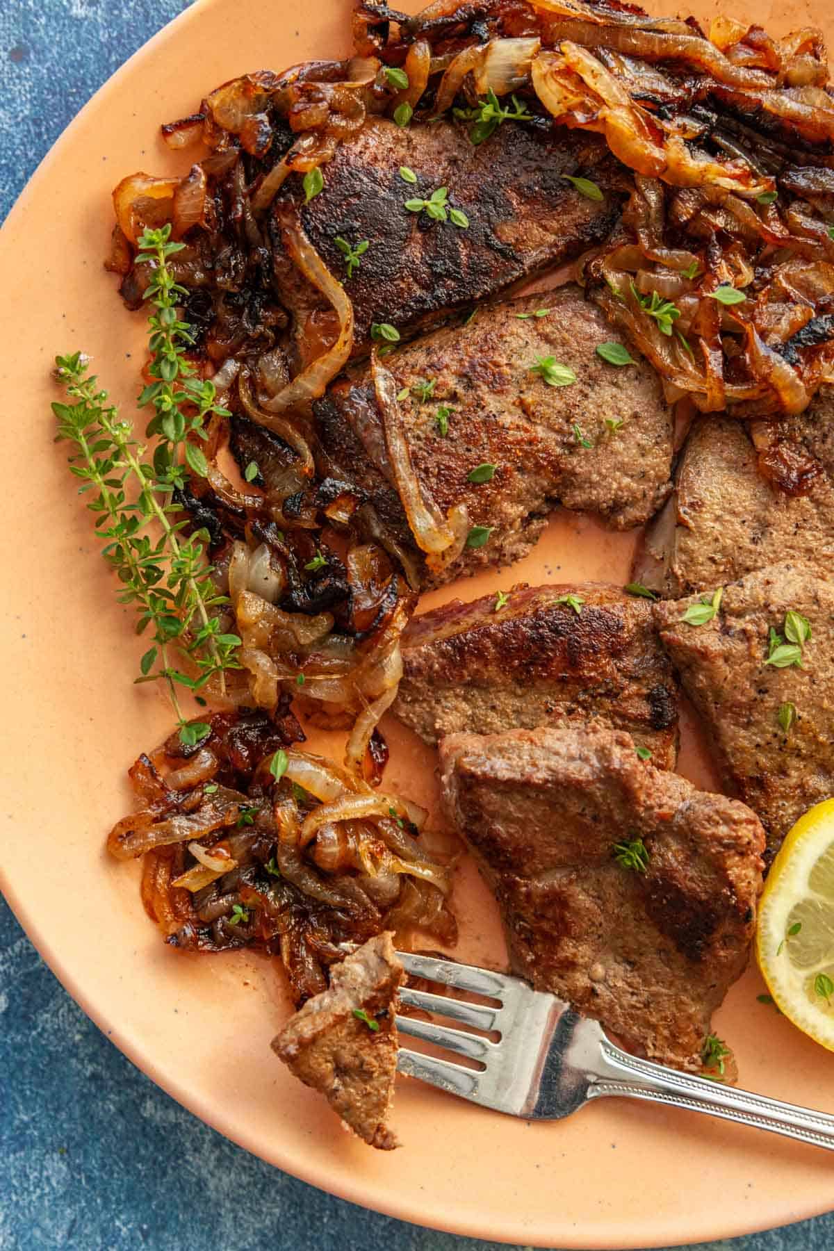 a plate of beef liver slices with a fork stabbing once piece