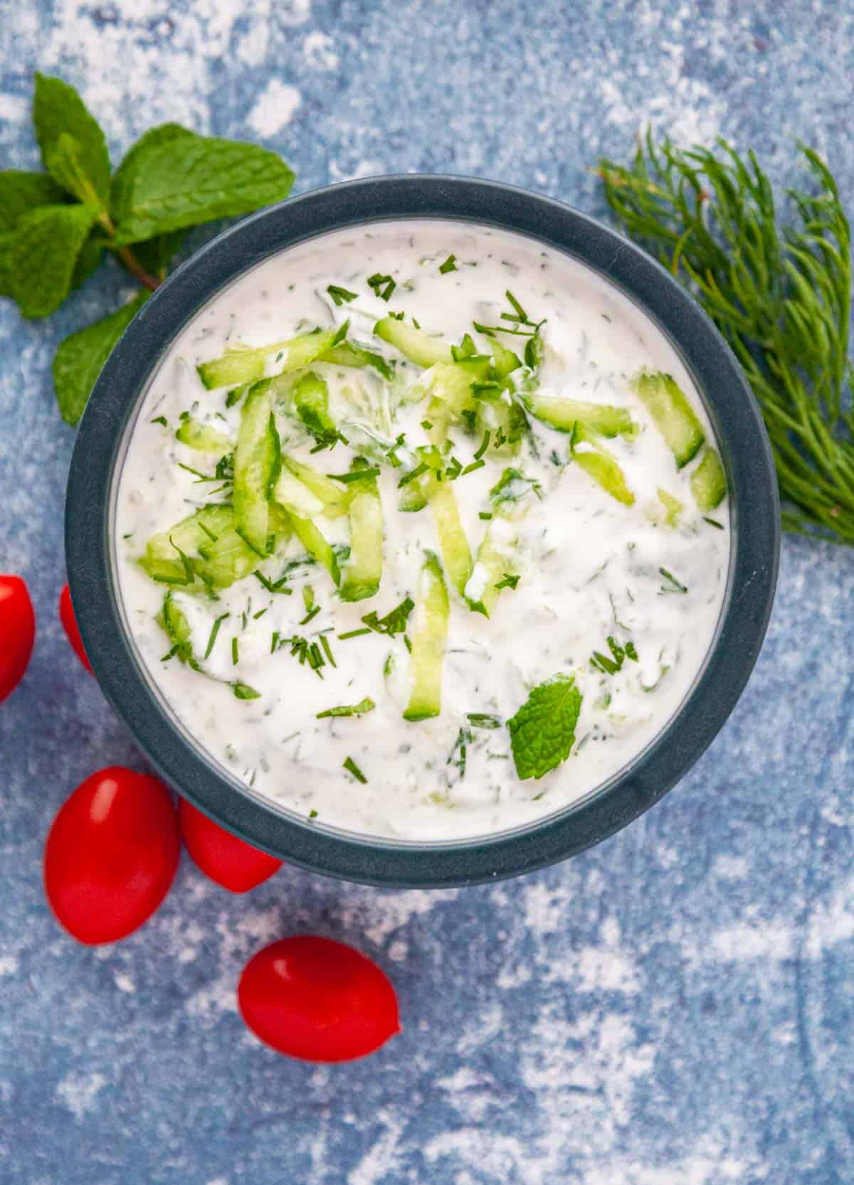 a bowl of greek yogurt with shredded cucumber and herbs