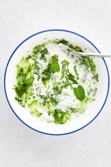 fresh herbs added to a bowl of yogurt