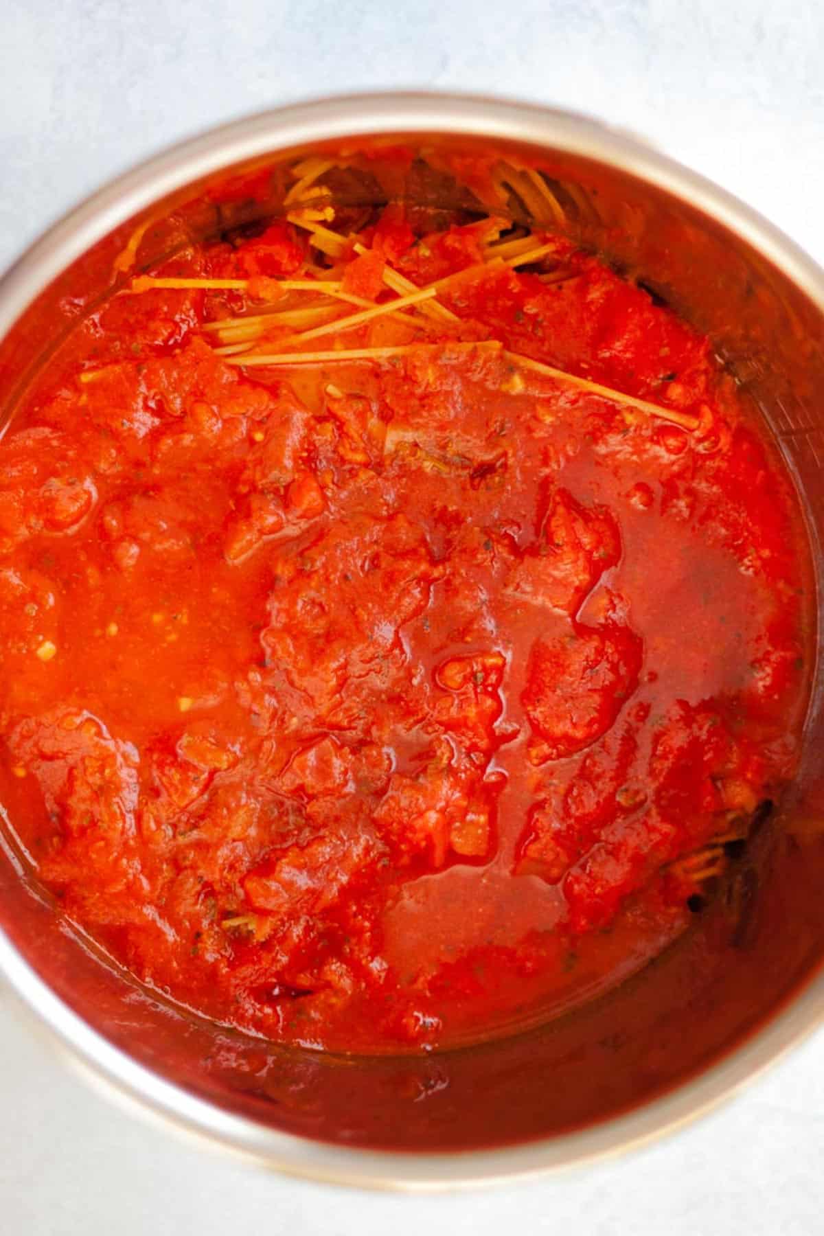 marinara sauce poured over uncooked spaghetti