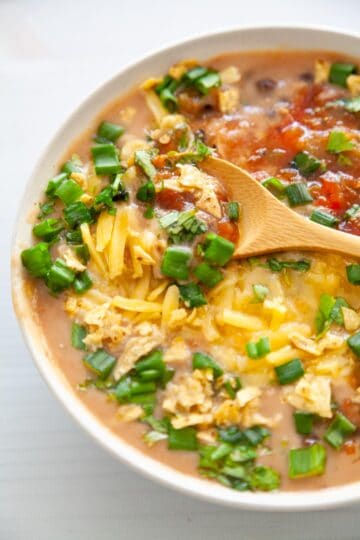 A bowl of creamy pinto beans soup with toppings.