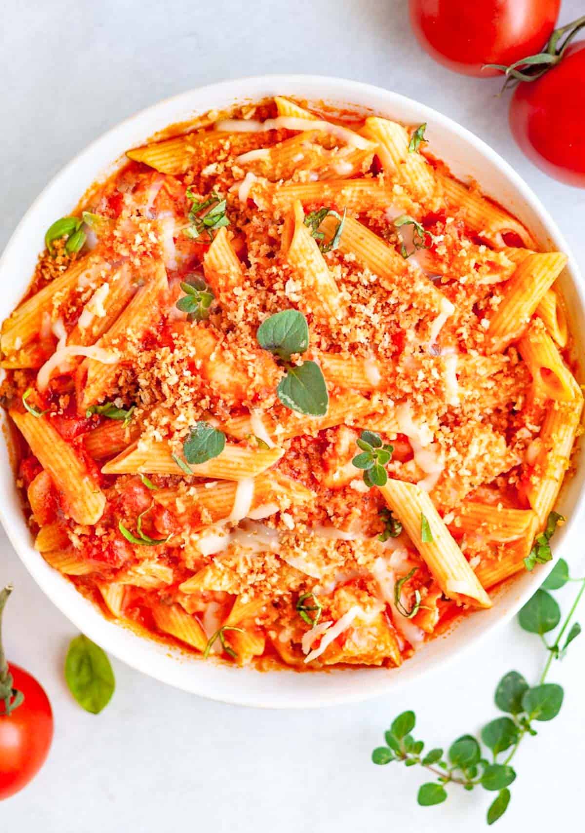 A bowl of penne pasta with red sauce and melted cheese.