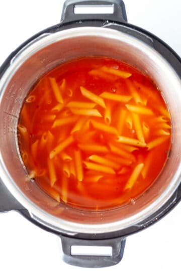 Water over uncooked penne pasta and marinara sauce in an Instant Pot.