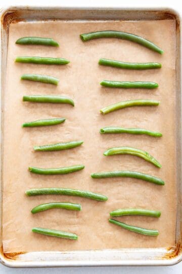 Frozezn, defrosted green beans on a sheet-pan.