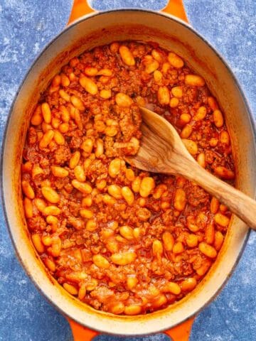 A Dutch oven filled with ground beef and white beans in sauce.