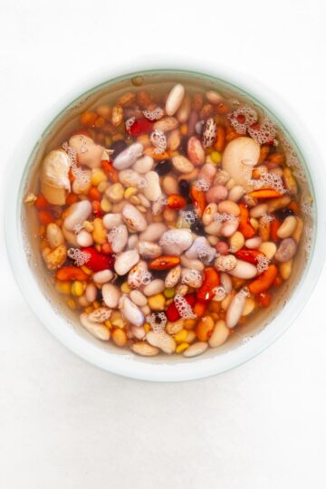 Dried beans soaking in a bowl of water.