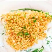A piece of white fish on a plate with cruncy panko and dill.