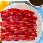 A plate of crispy turkey bacon with a coffee cup.